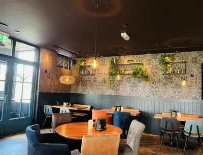 a restaurant with tables and chairs and plants on the wall at Millsight in Uitgeest