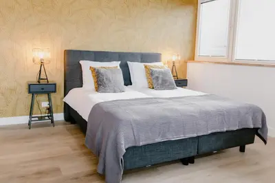 a bedroom with a large bed with two lamps at Millsight in Uitgeest