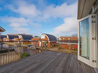 a balcony with a wooden deck with buildings in the background at Apartment Penthouse by Interhome in Uitgeest