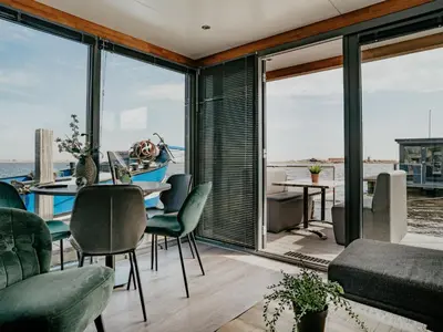 a dining room with a table and chairs and windows at Holiday Home De Meerparel-1 by Interhome in Uitgeest