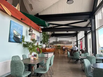 a restaurant with tables and chairs and a person in the background at Holiday Home De Meerparel-1 by Interhome in Uitgeest
