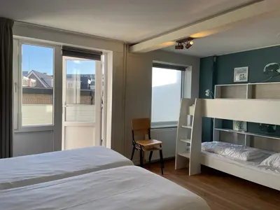 a bedroom with a bed and a desk and a window at Fijne vakantiehuizen 50 mtr van het strand in Egmond aan Zee