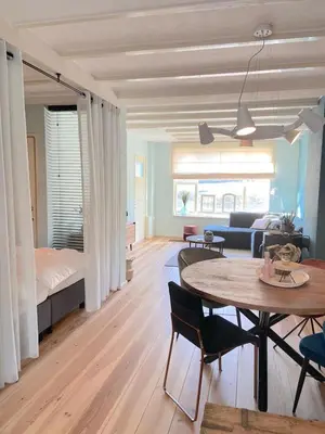 a living room with a table and a bedroom at Fijne vakantiehuizen 50 mtr van het strand in Egmond aan Zee