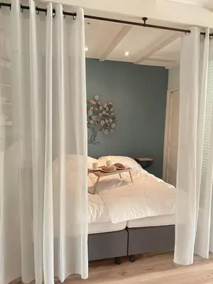 a bed with white curtains in a bedroom at Fijne vakantiehuizen 50 mtr van het strand in Egmond aan Zee