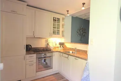 a kitchen with white cabinets and a sink at Fijne vakantiehuizen 50 mtr van het strand in Egmond aan Zee