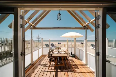 a dining table on a deck with a view of the beach at Thalassa Beach Houses in Zandvoort