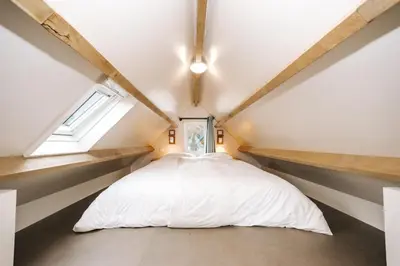 a bedroom with a white bed in a attic at Thalassa Beach Houses in Zandvoort