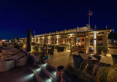 a rooftop bar with tables and chairs at night at Thalassa Beach Houses in Zandvoort