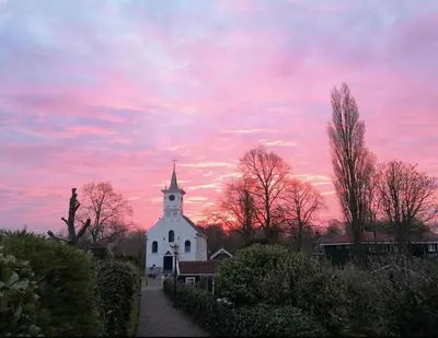a white church with a sunset in the background at HOMESTEAD Amsterdam in Amsterdam