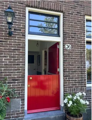 a red front door of a brick house with a red gate at HOMESTEAD Amsterdam in Amsterdam