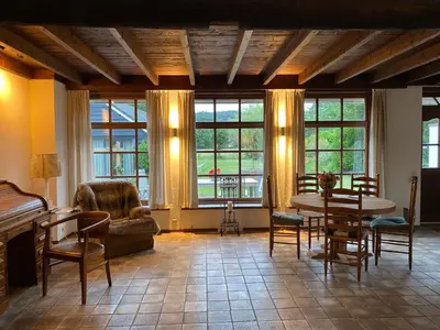 a living room with a table and chairs and windows at Koningshof in Schoorl