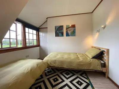 a bedroom with two beds and two windows at Koningshof in Schoorl
