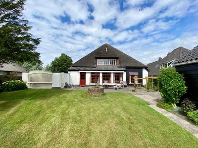 a house with a yard with a white fence at Koningshof in Schoorl