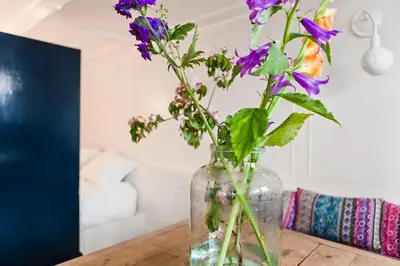 a vase filled with purple flowers on a table at Luna's Hideaway in Amsterdam