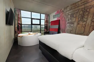 a bedroom with a tub and a bed and a window at Inntel Hotels Amsterdam Landmark in Amsterdam