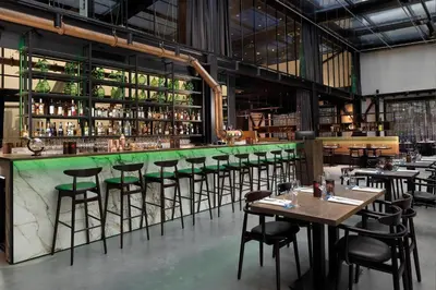 a restaurant with a green bar with tables and chairs at Inntel Hotels Amsterdam Landmark in Amsterdam