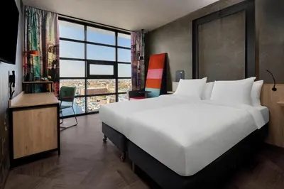 a large white bed in a room with a large window at Inntel Hotels Amsterdam Landmark in Amsterdam