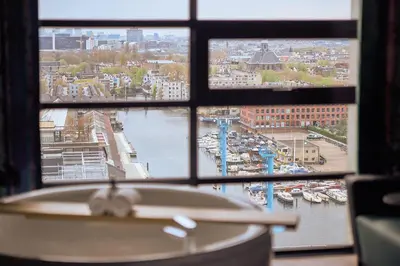 a bathroom with a view of a harbor from a window at Inntel Hotels Amsterdam Landmark in Amsterdam