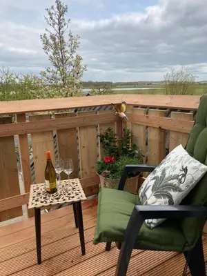 a bottle of wine sitting on a table on a deck at Vogelzicht in Koedijk