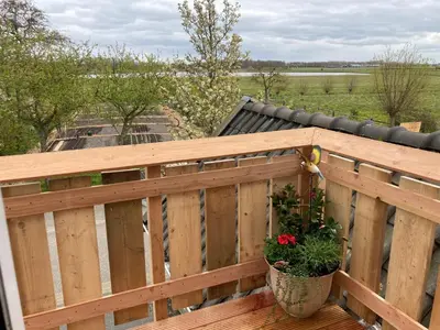 a wooden fence with a potted plant on a deck at Vogelzicht in Koedijk