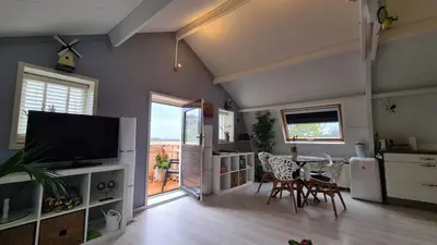 a living room with a television and a table and chairs at Vogelzicht in Koedijk