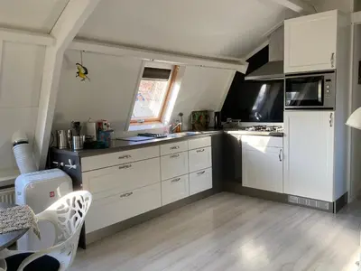 a kitchen with white cabinets and a white refrigerator at Vogelzicht in Koedijk