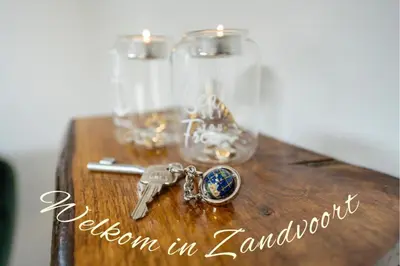 a wooden table with a key and two glasses at Cottage 44 - Free parking! in Zandvoort