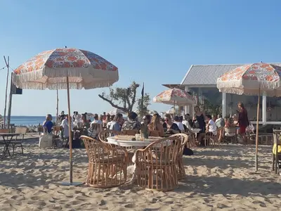 a group of people sitting at tables under umbrellas on the beach at Cottage 44 - Free parking! in Zandvoort