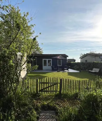 a yard with a fence and a house at Knus familiehuisje nabij Bergen en Schoorl in Warmenhuizen