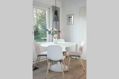 a dining room with a white table and chairs at Knus familiehuisje nabij Bergen en Schoorl in Warmenhuizen