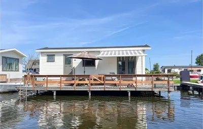 a house with an umbrella on a dock on the water at Lake Front Home In Breukelen in Breukelen