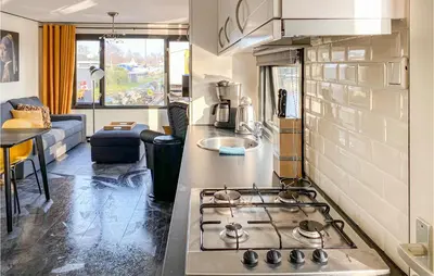 a kitchen with a stove top oven next to a living room at Lake Front Home In Breukelen in Breukelen