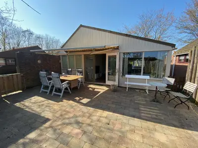 a patio with a table and chairs and a building at Rekerlanden 119 de Amandelbloesem in Schoorldam