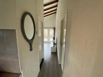 a mirror hanging on a wall in a hallway at Rekerlanden 119 de Amandelbloesem in Schoorldam