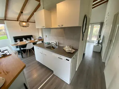 a kitchen with a sink and a table in a room at Rekerlanden 119 de Amandelbloesem in Schoorldam