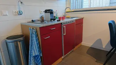a small kitchen with red cabinets and a sink at Goody in Zandvoort