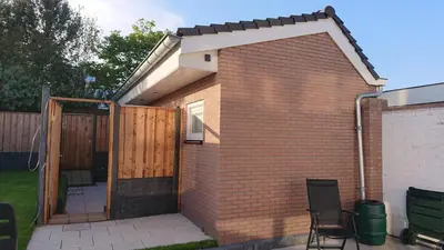 a brick building with a wooden door and a patio at Goody in Zandvoort