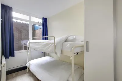 a room with two bunk beds and a window at DE TRINTEL op 1e verdieping met ruim terras en zeezicht in Egmond aan Zee