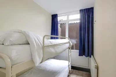 a room with two bunk beds and a window at DE TRINTEL op 1e verdieping met ruim terras en zeezicht in Egmond aan Zee