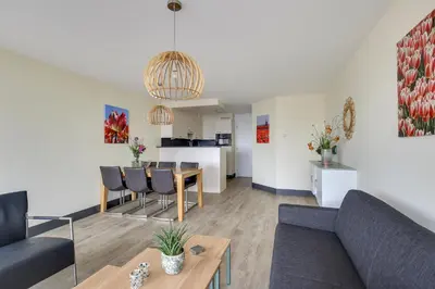 a living room with a couch and a table at DE TRINTEL op 1e verdieping met ruim terras en zeezicht in Egmond aan Zee