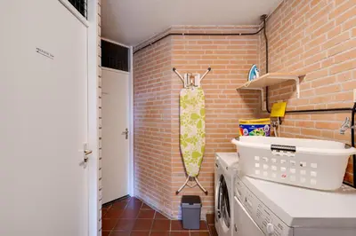 a kitchen with a washing machine and a brick wall at DE TRINTEL met zeezicht in Egmond aan Zee