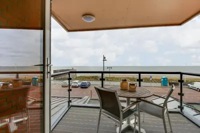 a balcony with a table and chairs and a view of a parking lot at DE TRINTEL met zeezicht in Egmond aan Zee