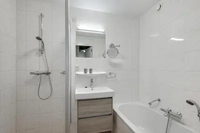 a white bathroom with a shower and a sink at DE TRINTEL met zeezicht in Egmond aan Zee
