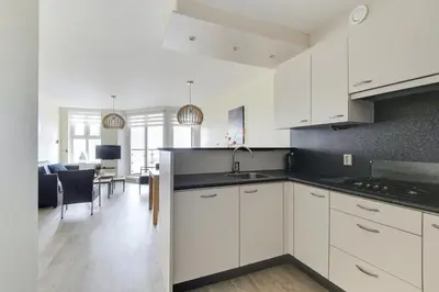 a kitchen with white cabinets and a living room at DE TRINTEL met zeezicht in Egmond aan Zee