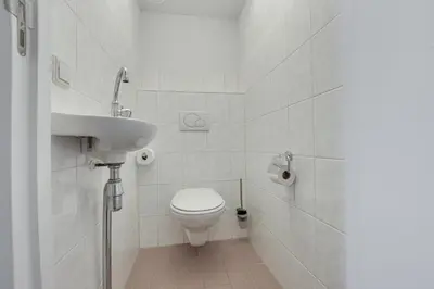 a white bathroom with a toilet and a sink at DE TRINTEL met zeezicht in Egmond aan Zee