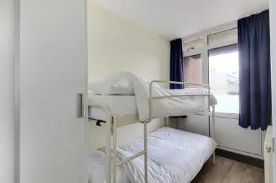 a bunk bed in a room with a window at DE TRINTEL met zeezicht in Egmond aan Zee