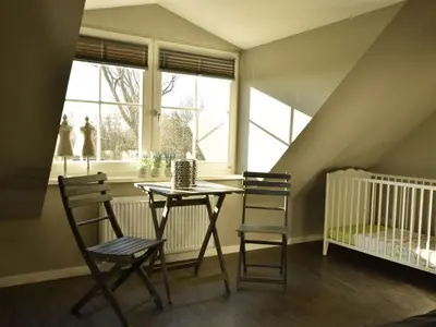 a dining room with a table and chairs and a crib at Modern holiday home near Schoorl and beach in Schoorldam