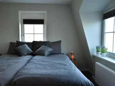 a bed in a bedroom with two windows at Modern holiday home near Schoorl and beach in Schoorldam