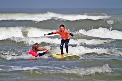 a young child riding a wave on a surfboard in the ocean at Villa Prinsenhof # Twaalf in Bergen