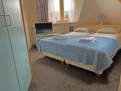 a bedroom with two beds and a desk and a television at Villa Prinsenhof # Tweeëntwintig in Bergen